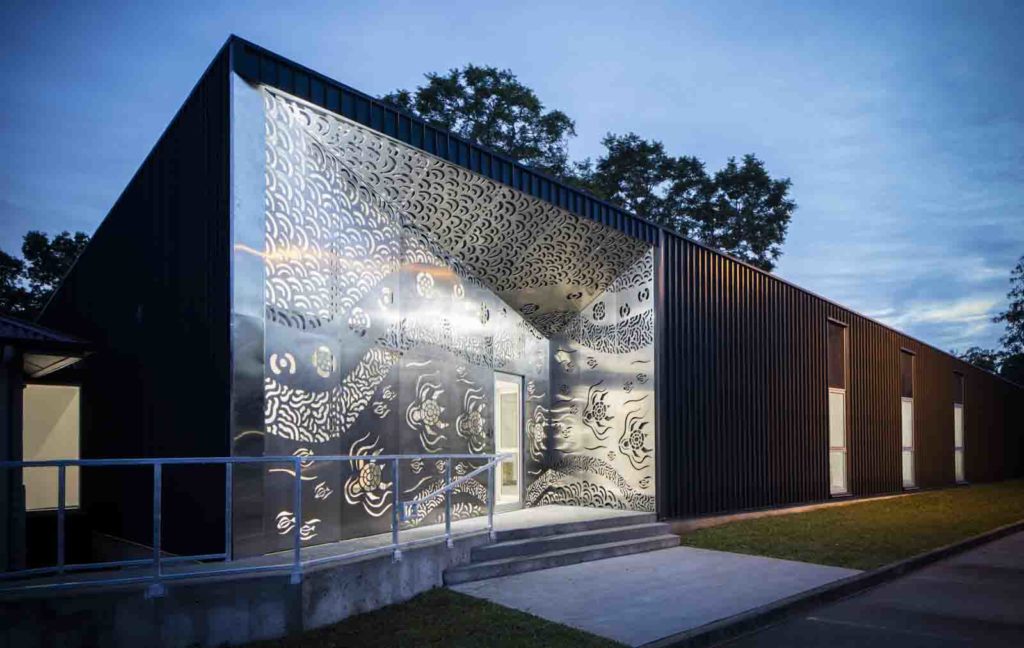Evening light, a building whose entry is through an Aboriginal art screen facade