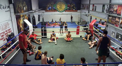 A boxing ring with a group of young Aboriginal men seated in a circle and two older men standing