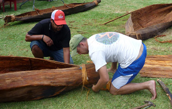 Cameron Andy and Jonathan Hill secure an end of one of the canoes with bark strips. Photo: David Payne/ANMM