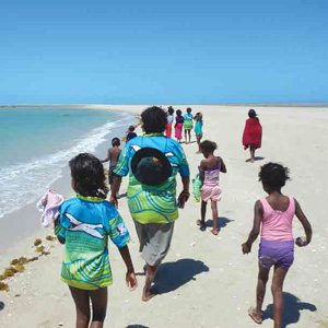 group of kids and an adult walk along the beach