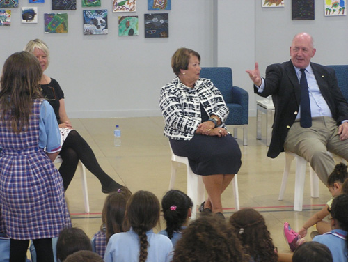 The Governor General Sir Peter Cosgrove and Lady Cosgrove  sitting infront of a group of children, answering questions.