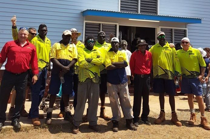 12 construction workers, mostly Yolngu men, standing in front of a building
