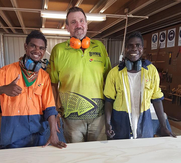 Two young Yolngu men, cabinet-maker apprentices, smiling, with an older white man