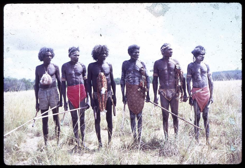 Yolngu land rights warriors: Wandjuk Marika, Roy Ḏaḏayŋa Marika, Mawalan Marika, Mathaman Marika, Milirrpum Marika and Ninimbitj Marika, standing on a grassy plain holding spears