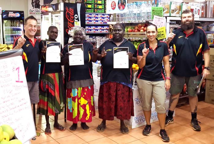 Six people in a shop, three holding certificates