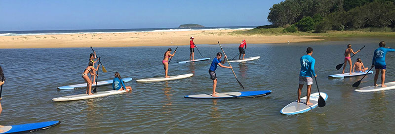 coastal waters landscape with a group of people on stand-up paddle boards in the foreground