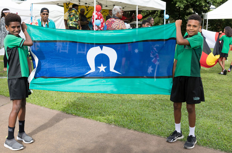 Two schoolboys happily holding the Torres Strait Islander flag