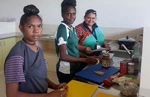 Young Aboriginal women preparing food in a kitchen