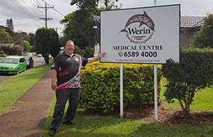 man standing proudly in front of a sign for Werin Aboriginal Corporation