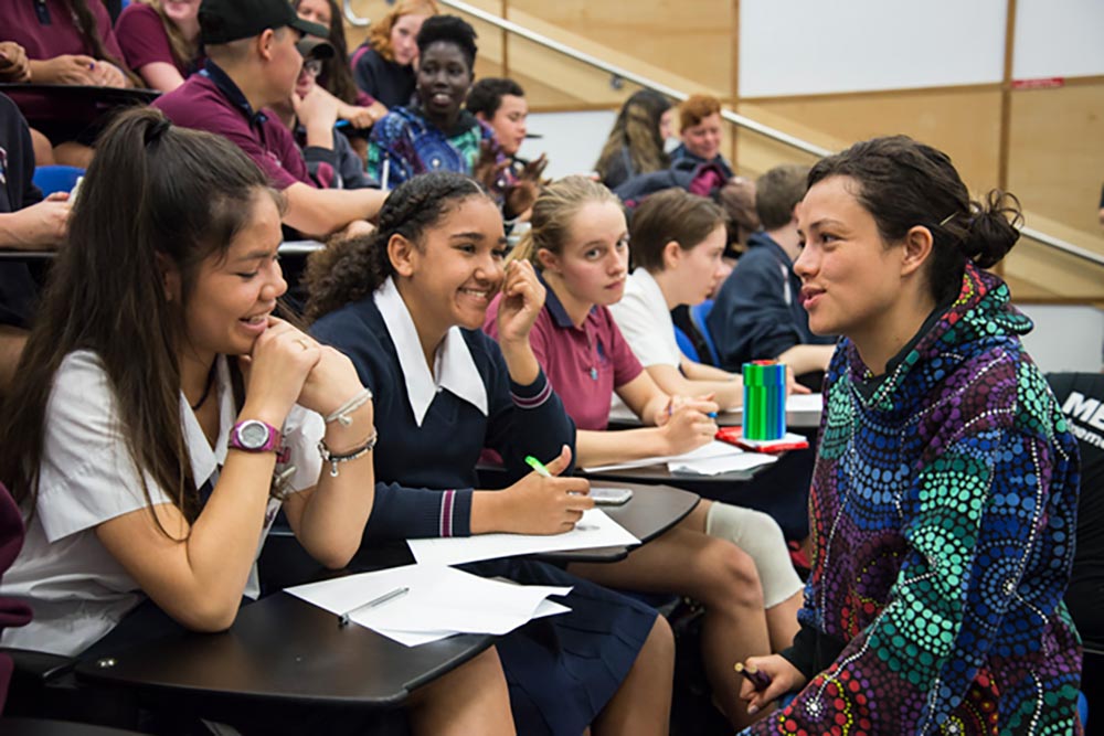 Young Aboriginal woman speaking to school students in a lecture theatre