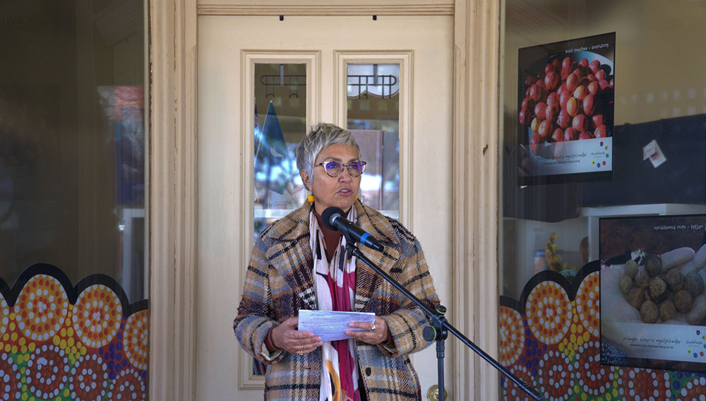 Jody Broun standing at a microphone in front of Goldfields Aboriginal Languages Centre