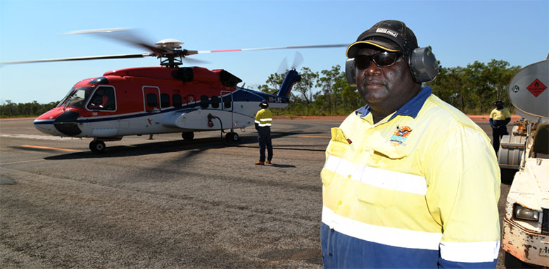 Aboriginal man standing in front of a helicopter being refuelled with the engine still running