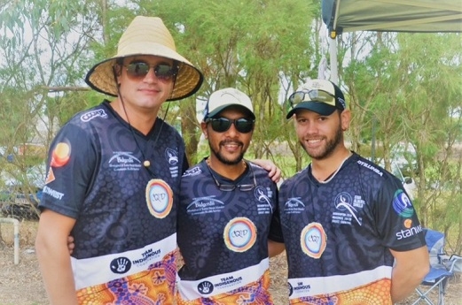 Three men wearing cricket shirts smile at the camera