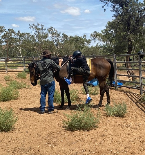 a person mounting a horse with the help of a man