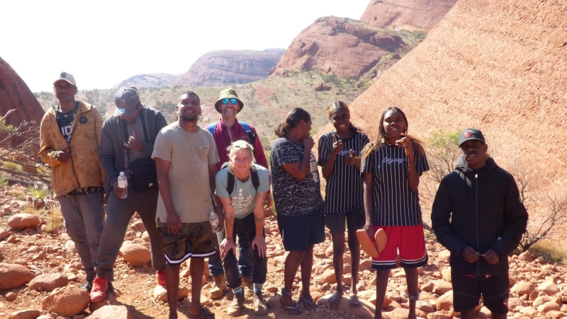 A group of people stand, smiling at the camera, in a rocky area