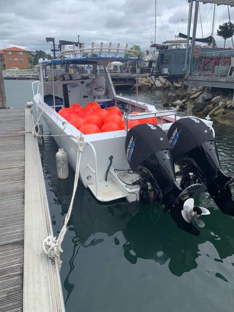 A boat with two outboard engines tied to the side of a jetty