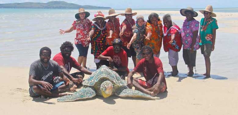 A group of people on a beach with a turtle