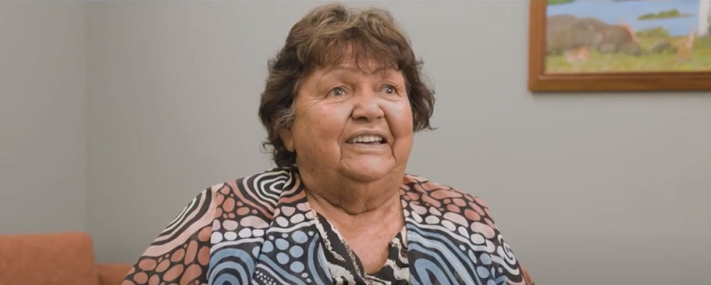 An older woman wearing a shirt with an Aboriginal print on it