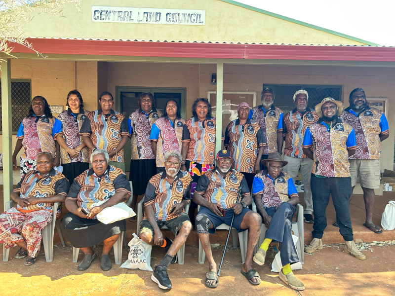 A group of 16 people stands in front of a building