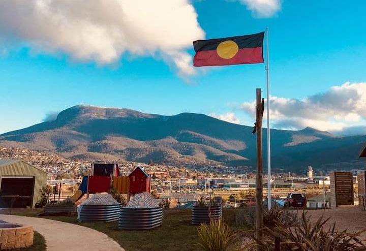 An Aboriginal flag flies over a path and children's playground