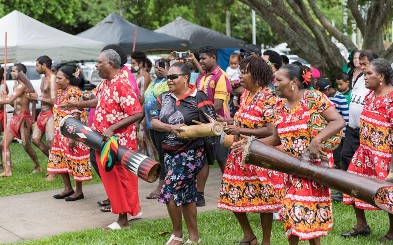 A group of people play long drums